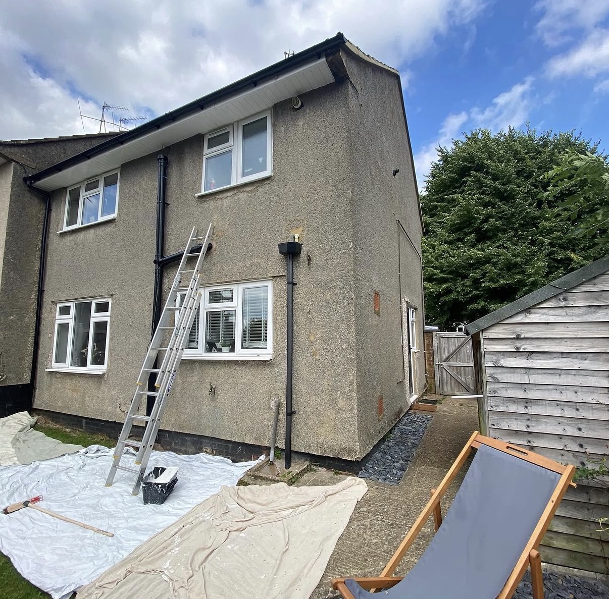 Two-story house with ladder and tarp.