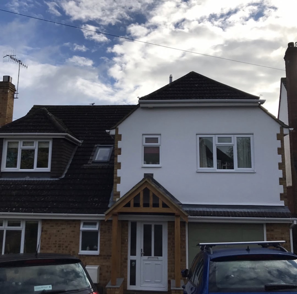 Two-story house with parked cars outside.